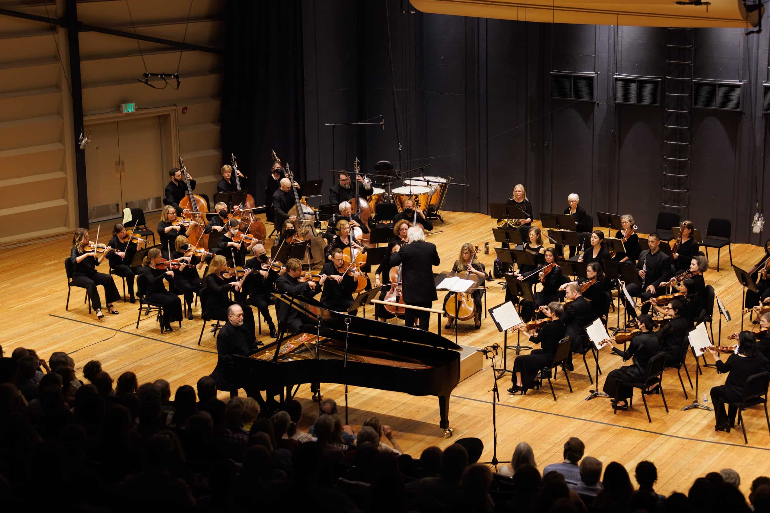 Garrick Ohlsson on stage during the July 2022 performance with the Grand Teton Music Festival Orchestra (also on stage) with audience at shown at the bottom